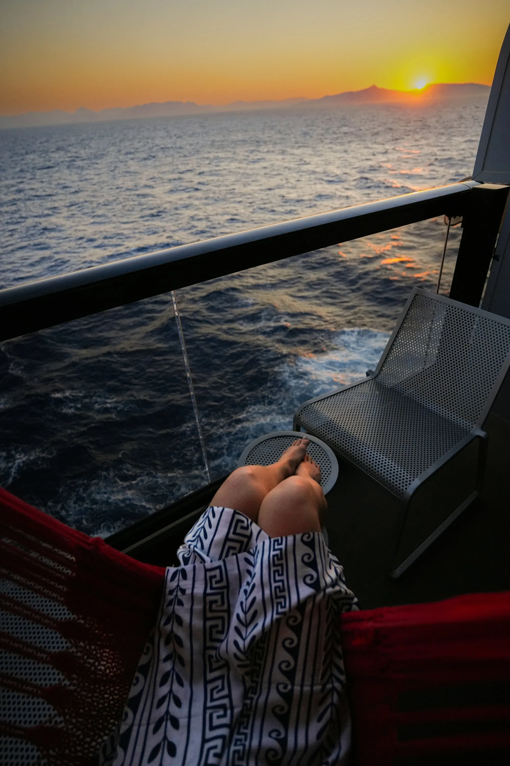 Silueta de una persona descansando en una hamaca frente al mar al atardecer