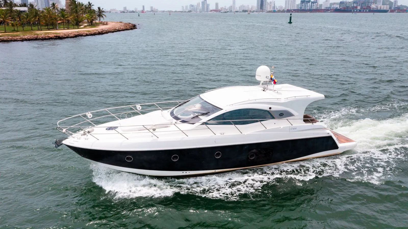 A yacht running along the Cartagena coastline with the city skyline behind it
