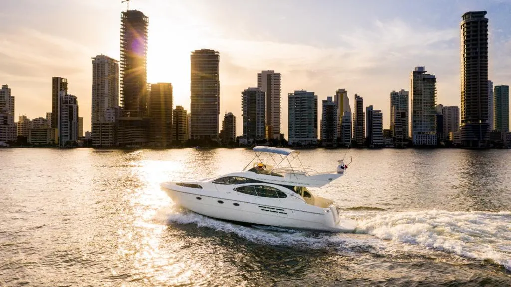 A private yacht arriving at golden hour with the Cartagena skyline behind it